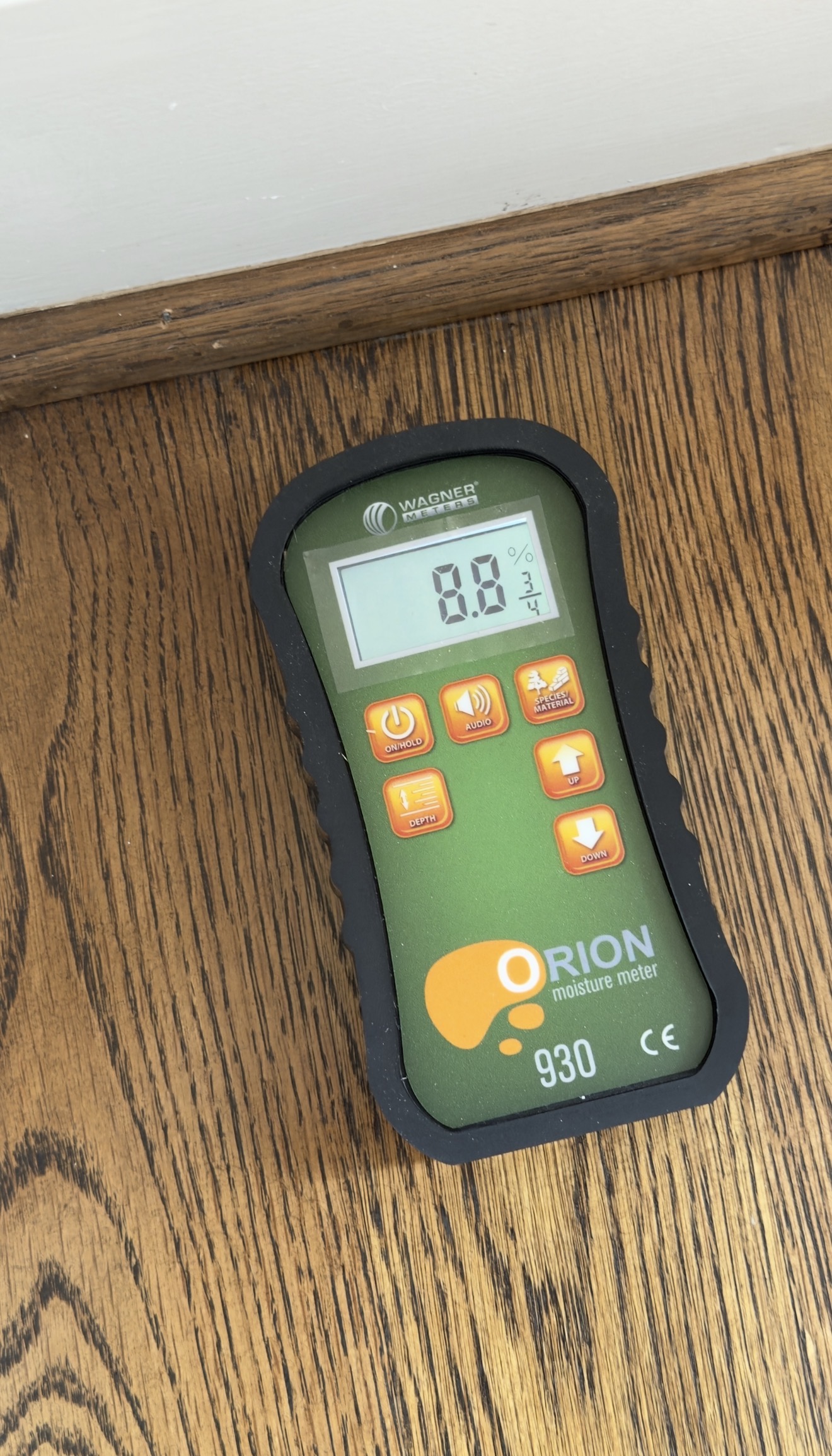 Moisture meter showing a reading on a hardwood floor board