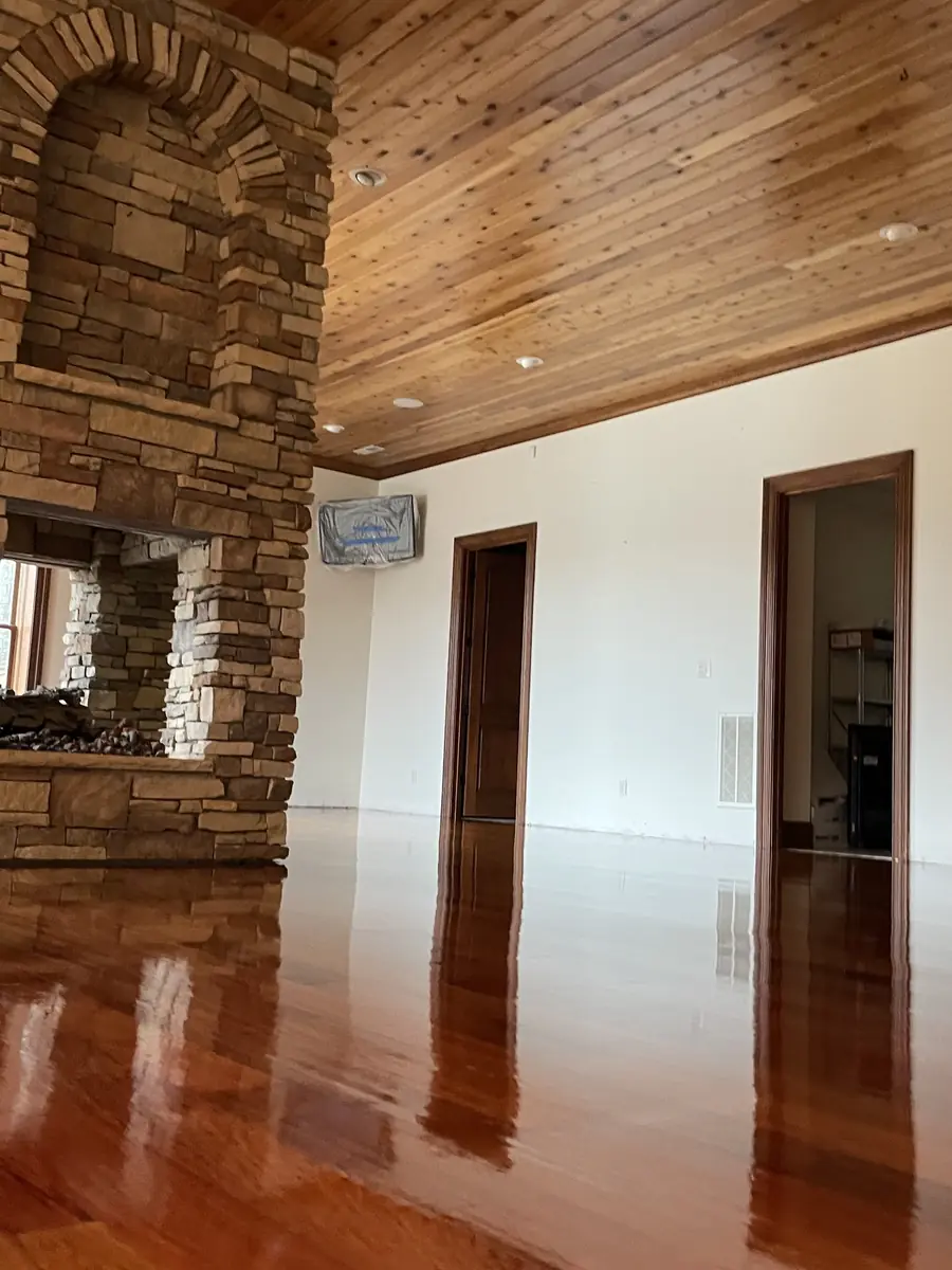 Refinished glossy hardwood floor in a Charlotte great room with stone fireplace
