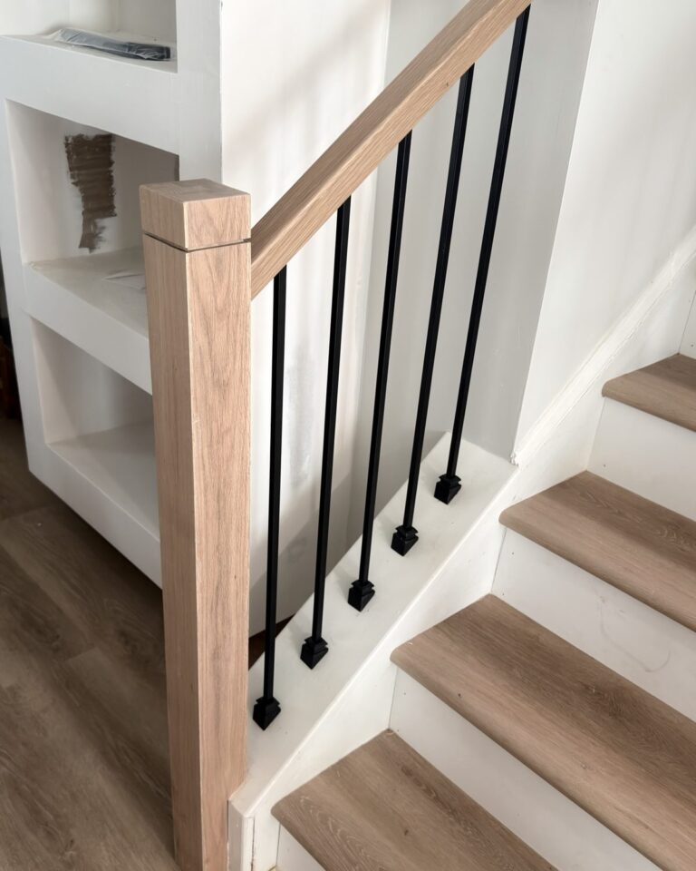 New square oak handrail and newel post with black balusters next to LVP stair treads