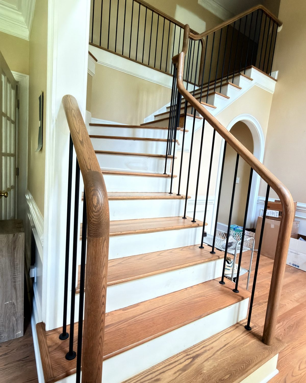 Staircase with a finished oak handrail, black iron balusters, oak treads and white risers